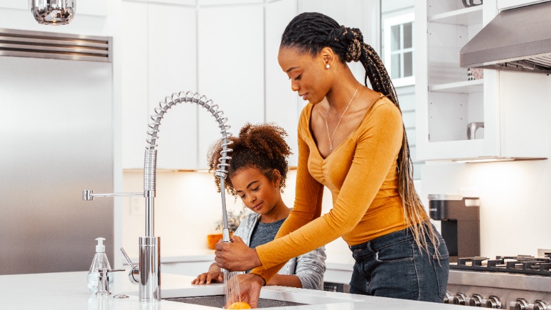 Mother and daughter using soft water at the kitchen sink